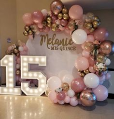 a large balloon arch with the number fifteen surrounded by pink, gold and white balloons