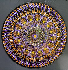 a plate with an orange, purple and yellow design on the front is sitting on a table