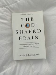 the god - shaped brain book is laying on a white bed sheet and it's title reads, the god - shaped brain