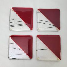 four square glass coasters with red and white designs on the sides, one has a diagonal design