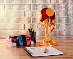 a game controller trophy sitting on top of a wooden table next to books and pens