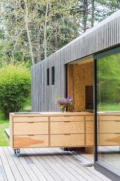 a large wooden dresser sitting on top of a wooden deck next to a forest filled with trees