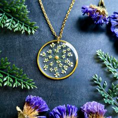 a necklace that has flowers in it on a table next to some purple and yellow flowers