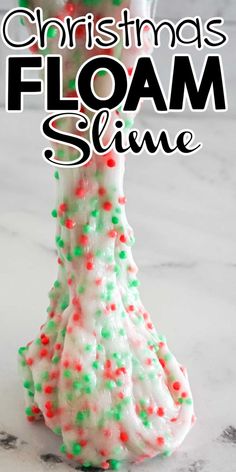 a glass filled with white and green slim slime next to a christmas tree ornament