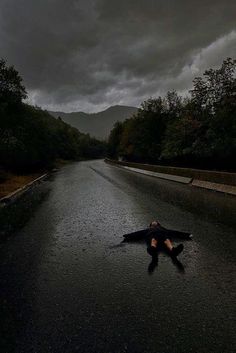 a person laying on the side of a wet road