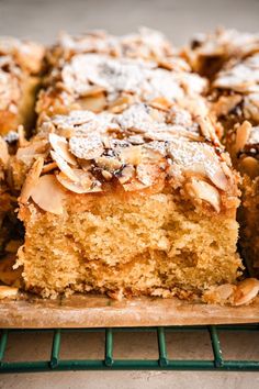 a close up of a cake on a cooling rack with almonds and powdered sugar