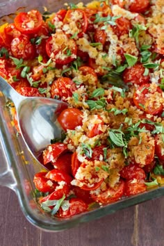 a glass casserole dish filled with tomatoes and bread crumbs, topped with parmesan cheese