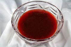 a glass bowl filled with red liquid on top of a white cloth