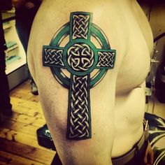 a cross tattoo on the back of a man's upper half - sleeved arm