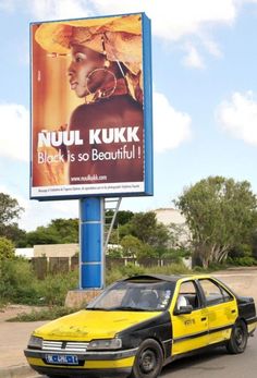 a yellow taxi cab is parked in front of a billboard for nuul kurk