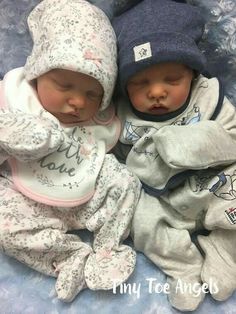 two baby babies laying next to each other on a blue blanket and wearing matching outfits