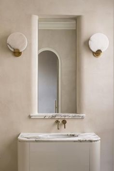 a white sink sitting under a mirror next to a wall mounted faucet in a bathroom