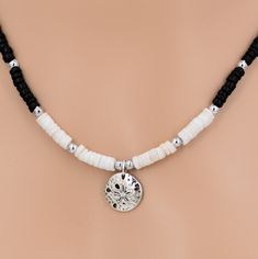 "Black Coconut, White Puka Shell and Silver Beads Necklace with Silver Alloy Sand Dollar Pendant Charm is 3/4\" or 19mm Diameter Choose 18 Inches length or 21 and 24 Inches by attaching a screw on coconut bead extender. See pictures In stock. Shipped daily from Florida USA JEWELRY CARE: All jewelry will feel the effects of improper care. You should remove jewelry before any type of bathing or water activity. Store your jewelry in zip lock type bags or compartmentalized jewelry boxes to avoid tangling and breakage." Black Heishi Beads For Beach, Beach Jewelry With Black Heishi Beads, Adjustable Polished Beads Necklace For Beach, Adjustable Polished Bead Necklaces For Beach, Adjustable Beaded Necklace For Beach, Adjustable Black Beads Jewelry For Beach, Adjustable Black Beaded Jewelry For Beach, Adjustable Beaded Necklaces With Polished Beads For Beach, Adjustable Polished Beaded Necklaces For Beach