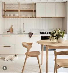 a cat laying on the floor next to a wooden table and chairs in a kitchen