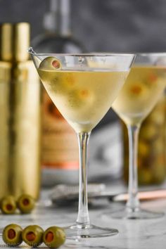 two martini glasses filled with white wine and olives