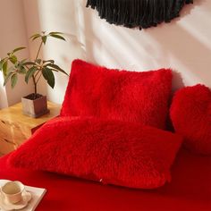 a red bed with two pillows and a cup on the side table next to it