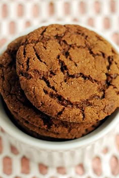 two chocolate cookies in a white bowl on a checkered tablecloth