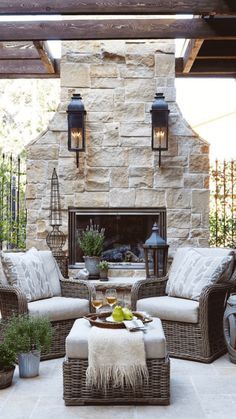 an outdoor living room with wicker furniture and stone fireplace