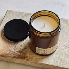 a candle sitting on top of a wooden block next to a black lidded container