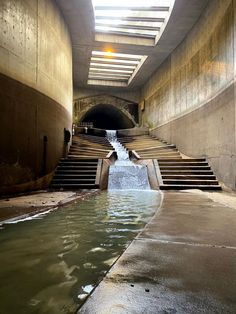 an underground tunnel with water flowing from it and stairs leading up to the exitway