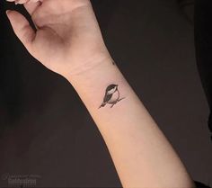 a small black and white bird tattoo on the wrist