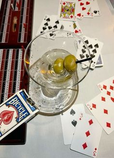 two olives in a martini glass surrounded by playing cards