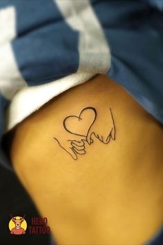 a woman's back with a tattoo on her stomach that has two hands holding a heart