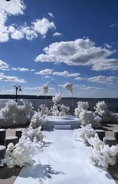 an outdoor wedding setup with white flowers on the ground and blue sky in the background