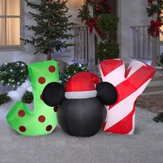 mickey mouse in front of a house decorated for christmas with candy canes and decorations