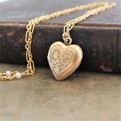 "This vintage locket is engraved with a floral design on the front; the reverse is plain. The gold filled heart, hallmarked 10k gf, opens revealing two compartments in which to place your favorite photos. The locket hangs from a new 14k gold filled cable chain accented with tiny white pearls at the clasp. Locket 24x21mm Necklace length 18\" (45cm) ✦All of our vintage lockets ship with complimentary insurance✦ ✤Our entire selection of lockets can be found here✤ http://www.etsy.com/shop/LexiandGem Brass Heart Pendant Wedding Jewelry, Brass Heart Pendant Jewelry For Wedding, Heart-shaped Brass Jewelry For Wedding, Heart-shaped Brass Wedding Jewelry, Gold Jewelry With Engraving Option For Wedding, Antique Gold Brass Necklace For Wedding, Antique Gold Brass Jewelry For Wedding, Traditional Heart Jewelry For Wedding, Antique Gold Necklace With Intricate Design For Weddings