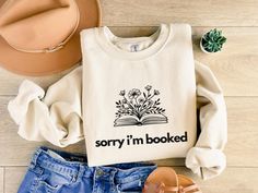 A cozy sorry i'm booked sweatshirt designed for Romantasy readers, Booktok enthusiasts, and lovers of dark romance and smut. This floral book-themed sweatshirt is perfect for those looking for a comfy and stylish piece to wear during colder months. It's ideal for snuggling up with a good book or adding a touch of literary flair to your outfit. Product features - Made with a medium-heavy fabric blend of 50% cotton and 50% polyester for a cozy feel - Ribbed knit collar with seam for shape retentio Hogwarts House Colors, Just One More Chapter, Librarian Shirt, One More Chapter, Gifts For Librarians, Gifts For Bookworms, Book Shirts, Gifts For Readers, Look Plus