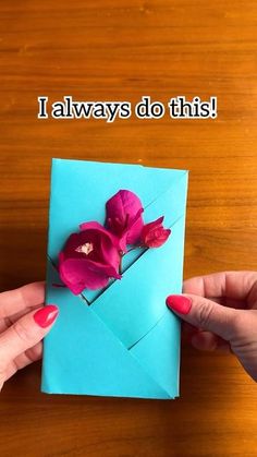 two hands holding an envelope with flowers in it and the words i always do this