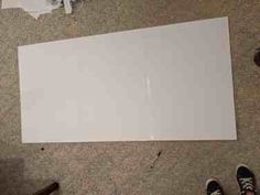 two people standing on the floor next to a large sheet of white paper that has been cut in half