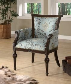 a blue chair sitting on top of a hard wood floor next to a rug and window