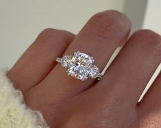 a woman's hand with a three stone diamond ring on top of her finger