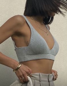 a woman in grey sports bra top and sweatpants with her hand on her hip