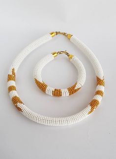 White and gold beaded necklace , African beaded necklace , Beaded necklace with matching bangle , Jewelry from Africa This necklace is 100% handcrafted using original fine beads. *Necklace comes with 1 matching bangle. The necklace is 18 inches long( round the neck). **Buy multiple items and pay shipping for 1 item only.The rest ships free. Thank you for visiting my shop. More neckleces here; https://www.etsy.com/shop/TribalTess?ref=seller-platform-mcnav&section_id=21306083 Back to my shop; White And Gold Beads For Jewelry Making, White Beaded Necklaces With Large Beads, White Beaded Necklace With Large Beads, White Beaded Necklace With Large Round Beads, White Gold Beads For Jewelry Making, Traditional White Bracelets With Polished Beads, White Beaded Chain Necklace, Traditional White Jewelry With Tiny Beads, White Necklace With Gold Beads As Gift