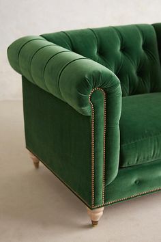 a green velvet couch sitting on top of a white floor