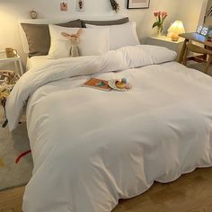 a bed with white sheets and pillows on top of it in a room filled with pictures