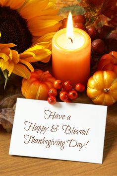 a happy thanksgiving message with sunflowers and pumpkins next to a lit candle