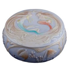 a blue and white box with two mermaids on it's sides, in the shape of a shell