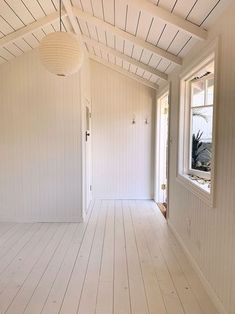 an empty room with white walls and wood flooring on the side of the house