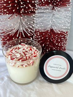 a glass jar filled with candy canes next to a red and white christmas tree