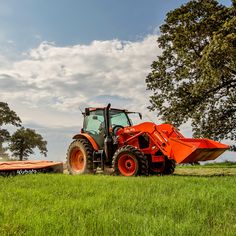 an orange tractor is driving through the grass