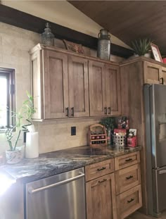 a kitchen with wooden cabinets and granite counter tops, stainless steel refrigerator and dishwasher