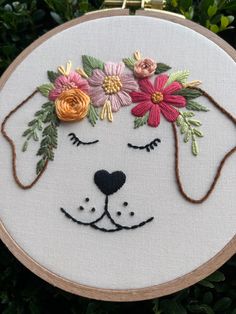 a white dog with flowers on it's head is shown in a embroidery hoop