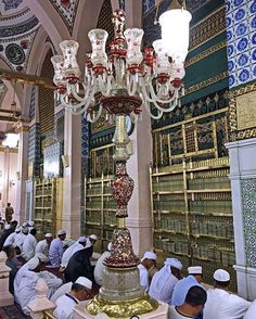 men praying in a large room with chandelier and bookshelves on the walls