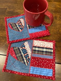 two red mug holders on top of a wooden table next to a blue and white quilt