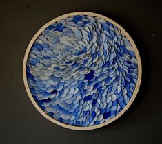 a blue and white plate sitting on top of a black table next to a wall