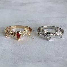 three rings with different designs on them sitting on a marble counter top, one has a heart and the other is a dragon